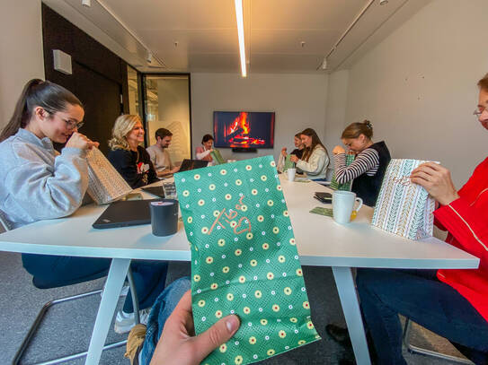 Get together Personen am Tisch schauen in ihre Weihnachtstüten