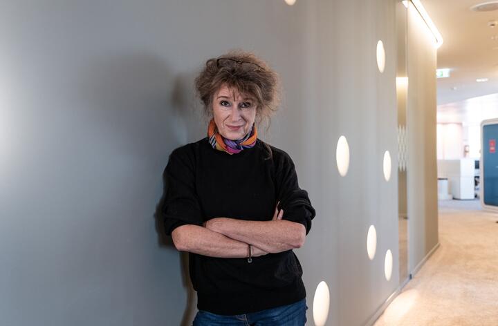 Unsere Kollegin lehnt sich an einer Wand an mit verschränkt die Armen